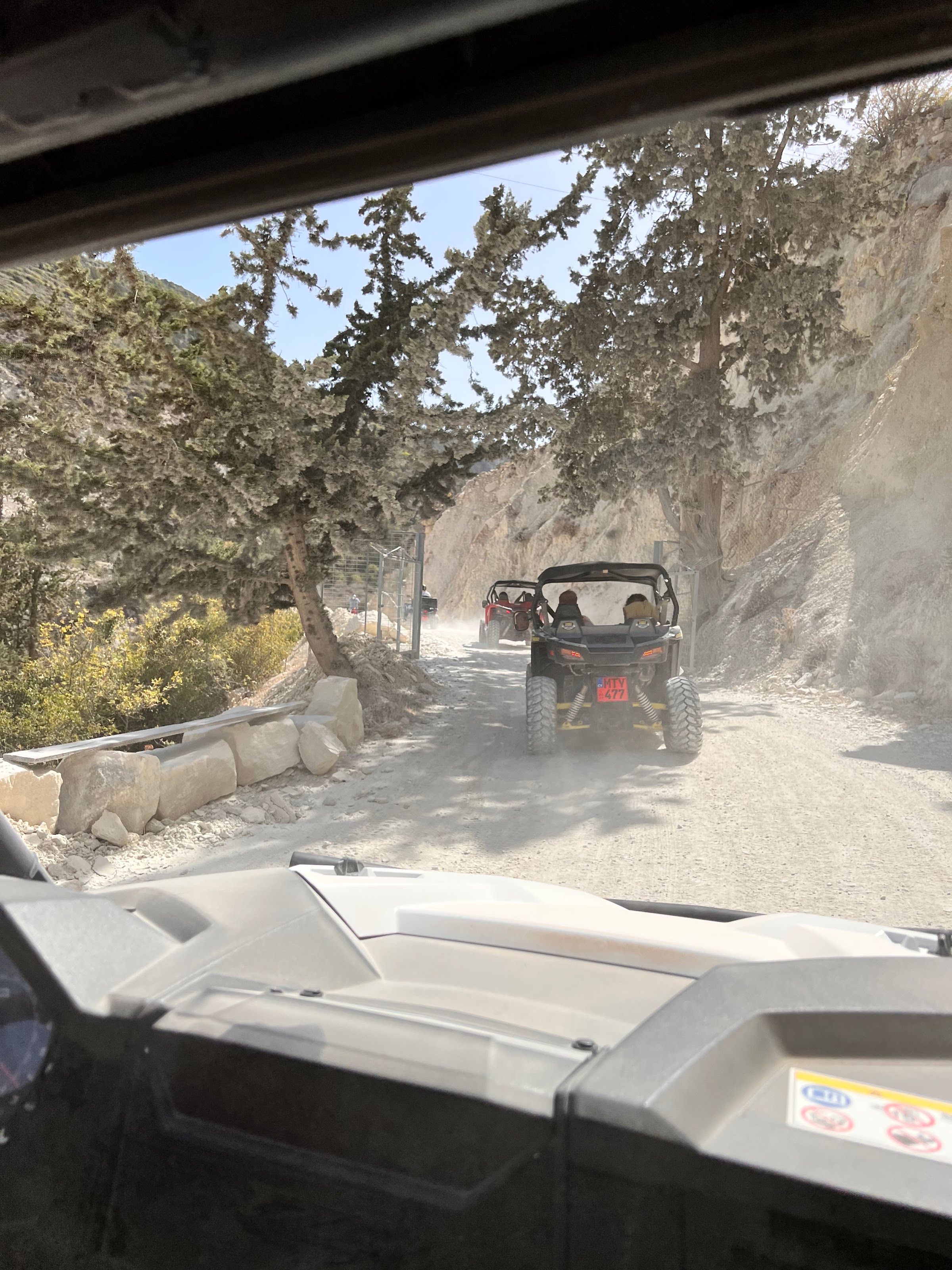 Convoy of buggies driving through a dusty mountain canyon trail